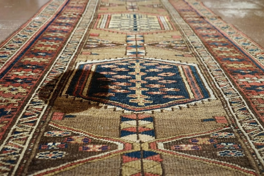 Tapis ancien présentant une tache sombre avant intervention